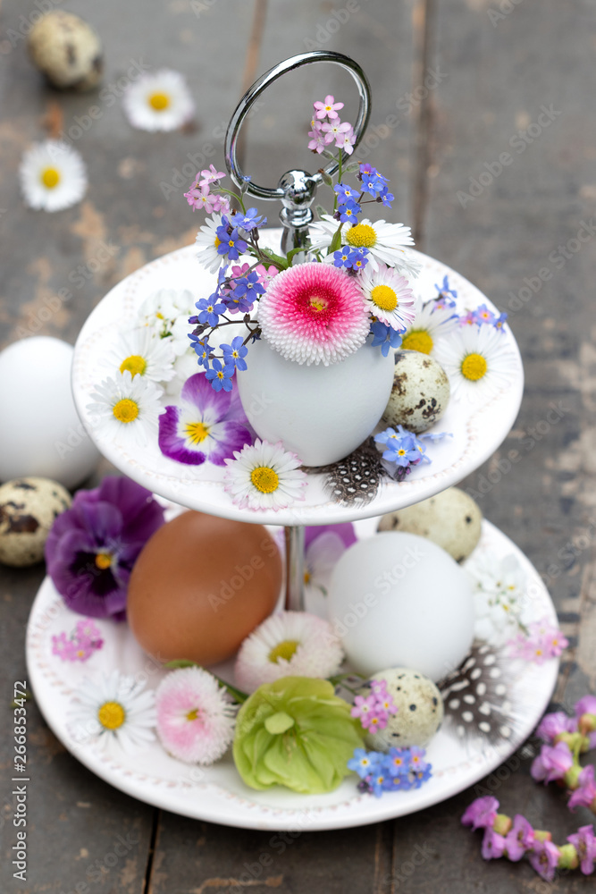 Osterdekoration mit Frühlingsblumen und Eiern auf Porzellan-Etagere Osterdekoration mit Frühlingsblumen und Eiern auf Porzellan-Etagere
