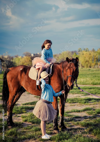 Cute sisters posing wit horse. © Alona