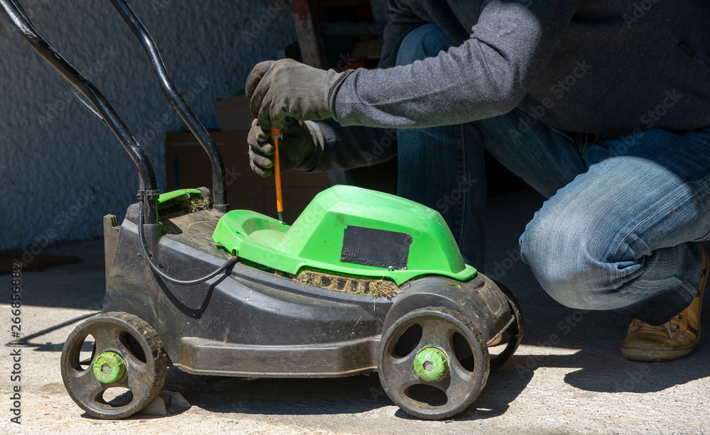 man repairing an electric lawn mower
