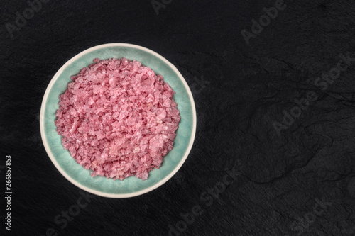 A bowl of pink Himalayan sea salt, shot from the top on a black background with a place for text