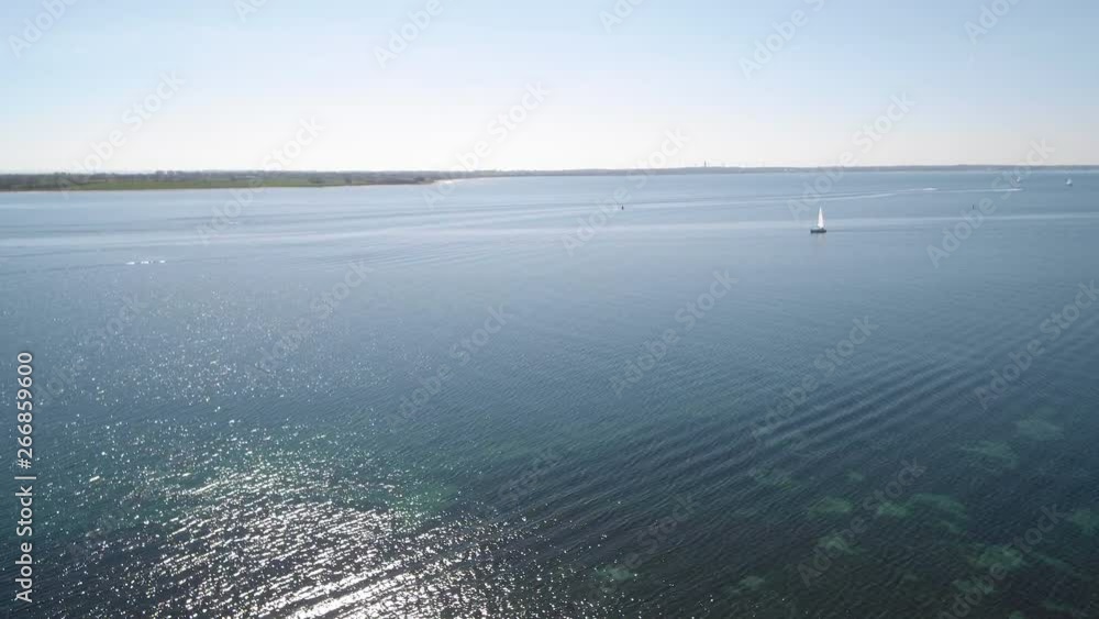 Drone flying over water with sun sparkles and sailingboat Drone flying over water with sun sparkles and sailingboat