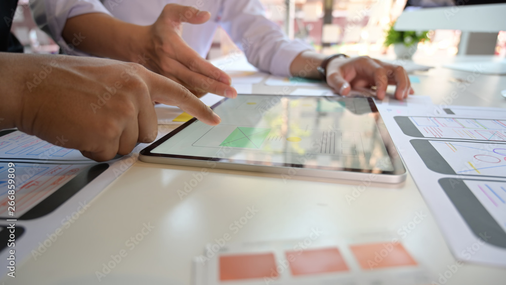 Obraz premium Team UI designers design and sketch lay-out with interface on tablet pc