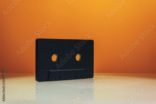 Black classic magnetic cassette tape on a white taable and ogrange background. photo