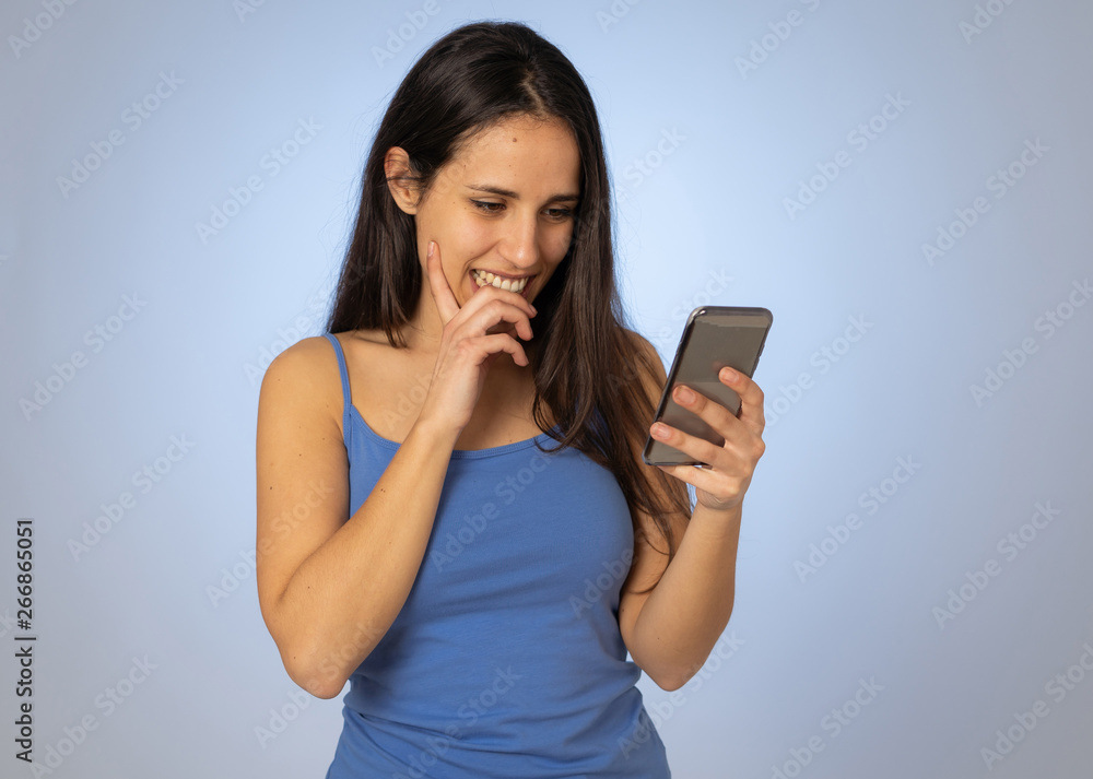 Attractive young woman looking at mobile smart phone shocked and surprised having lost of likes Attractive young woman looking at mobile smart phone shocked and surprised having lost of likes