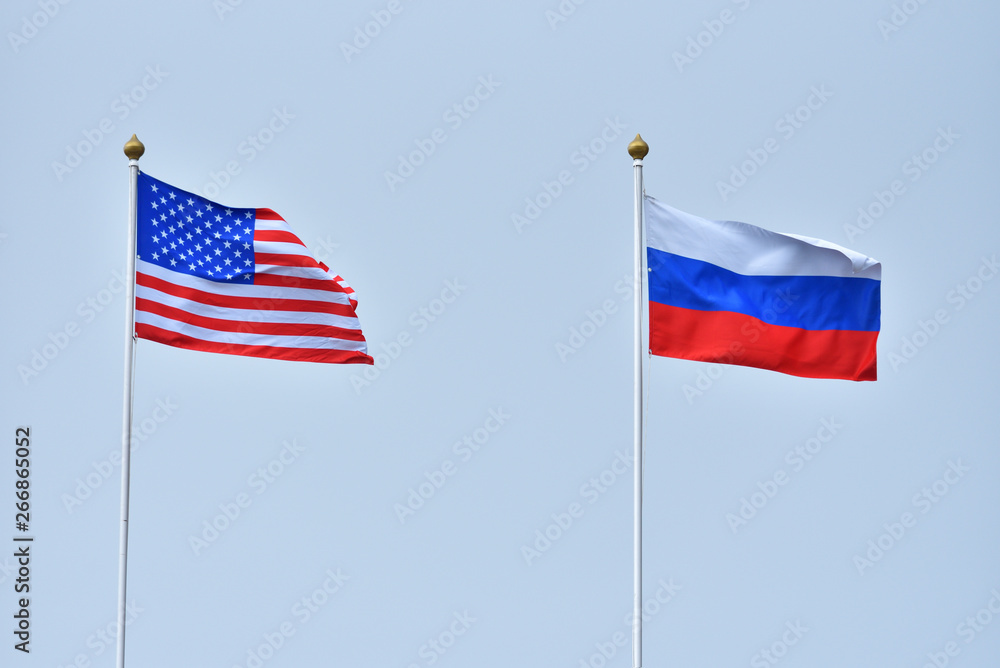 Beautiful and bright flags of the Russian Federation and the United States of America against the sky. Flags of Russia and America as a symbol of cooperation and friendship