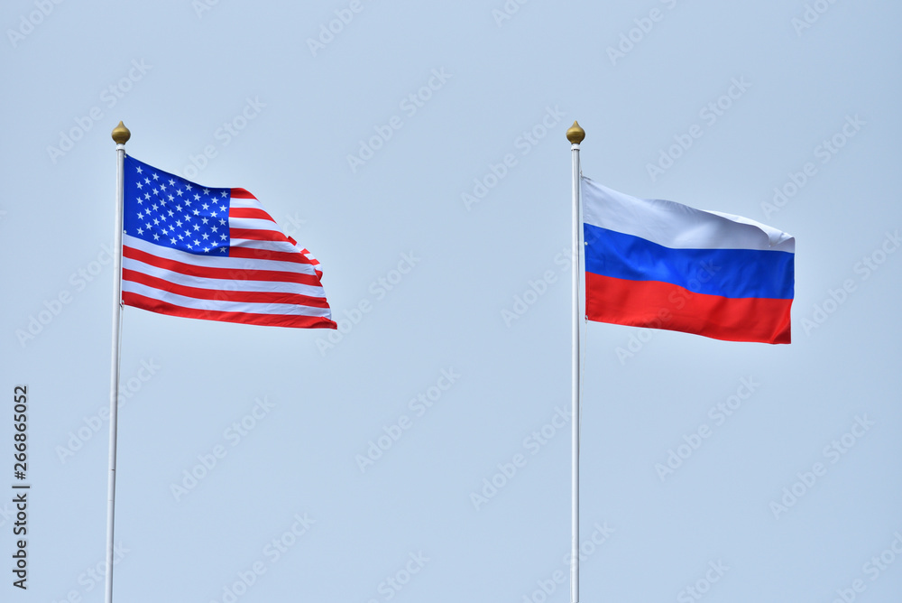 Beautiful and bright flags of the Russian Federation and the United States of America against the sky. Flags of Russia and America as a symbol of cooperation and friendship Beautiful and bright flags of the Russian Federation and the United States of America against the sky. Flags of Russia and America as a symbol of cooperation and friendship