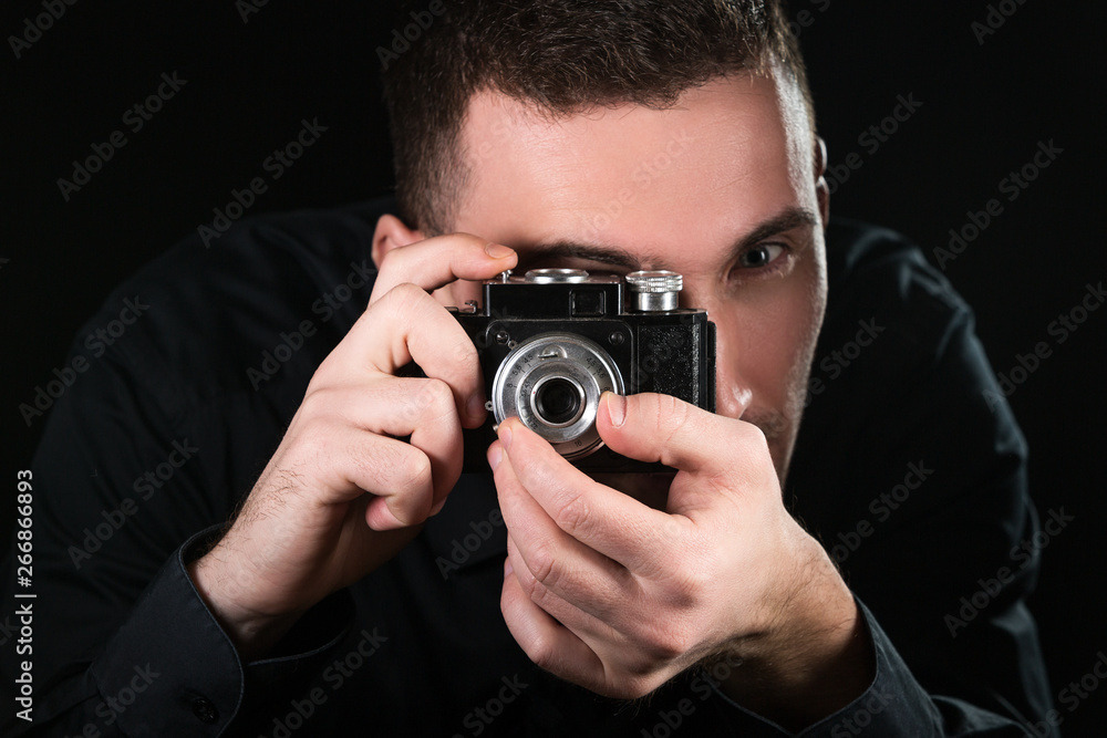 Man photographer holding a retro photo camera. Shooting process. Photographer looks at viewfinder. Man photographer holding a retro photo camera. Shooting process. Photographer looks at viewfinder.