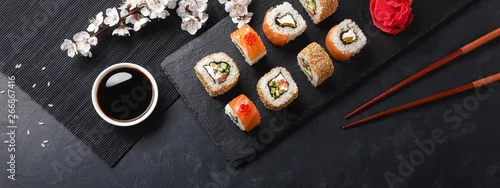 Panel kuchenny z motywem Set of sushi and maki rolls with branch of white flowers on stone table