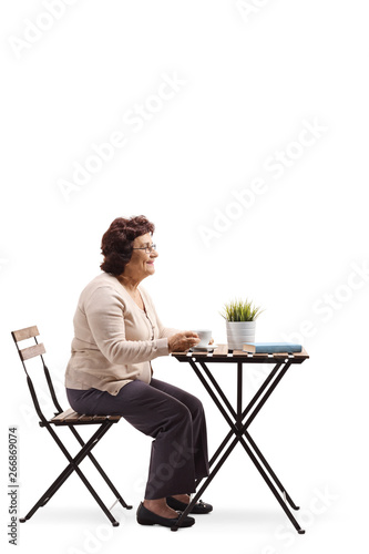 Elderly woman drinking coffee at a table alone