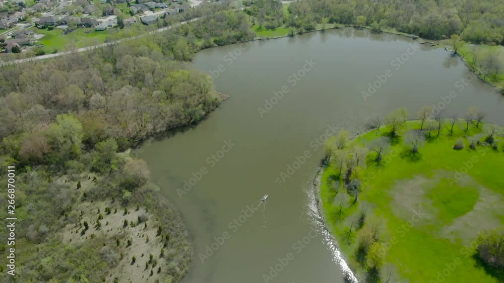 Aerial vertical reveal of a suburban area with houses near a small lake in western suburbs of Chicago, Illinois. Tampier Slough lake, Tampier Slough woods, near Lemont, Illinois. Aerial vertical reveal of a suburban area with houses near a small lake in western suburbs of Chicago, Illinois. Tampier Slough lake, Tampier Slough woods, near Lemont, Illinois.