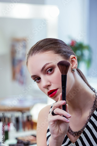Nice young woman standing with a powder brush