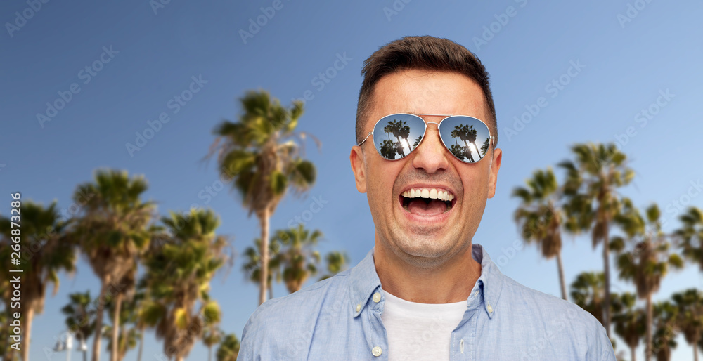 summer holidays, vacation and emotions concept - laughing middle aged latin man in shirt and sunglasses over palm trees and blue sky at venice beach in california background summer holidays, vacation and emotions concept - laughing middle aged latin man in shirt and sunglasses over palm trees and blue sky at venice beach in california background