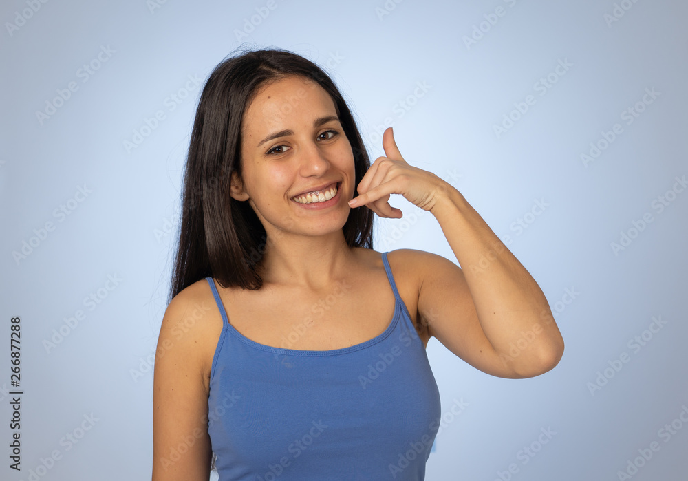 Pretty teenager girl or young woman showing Call Me gesture with cute look Pretty teenager girl or young woman showing Call Me gesture with cute look