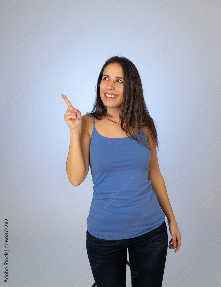 Charming smiling young woman pointing finger at empty copy space for advertisement Charming smiling young woman pointing finger at empty copy space for advertisement