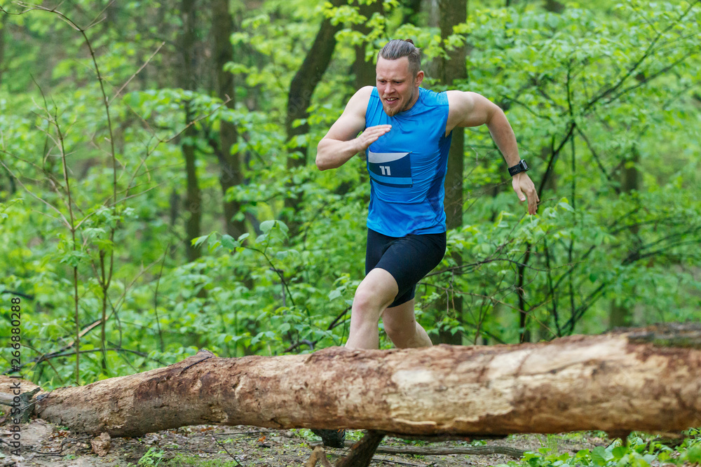 Young sporty man running trail cross in the forest