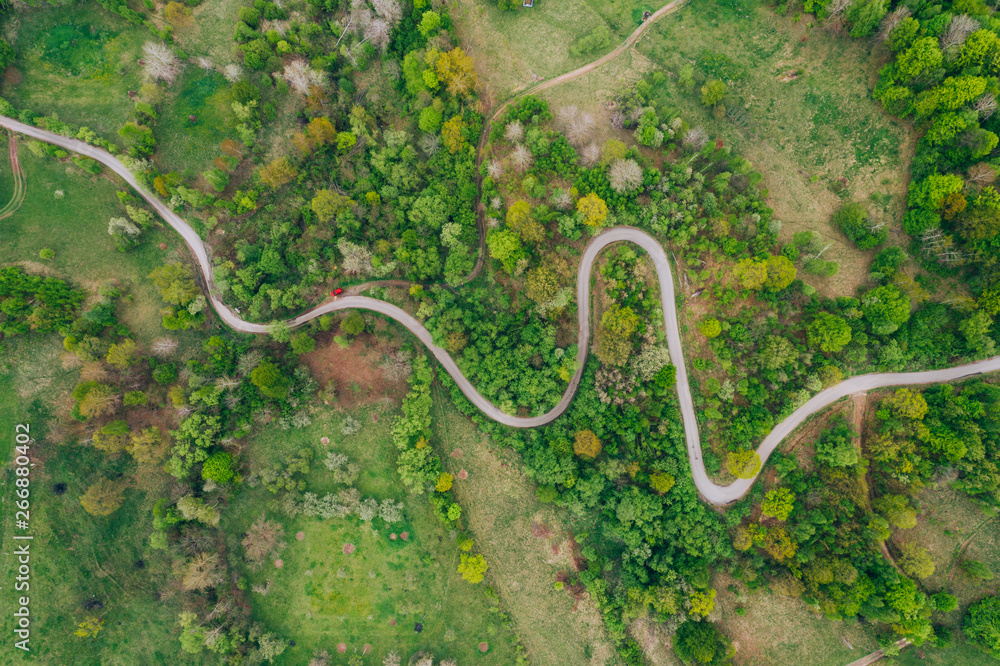 Drone view of green meadows, small houses and roads in Transylvania, Romania.