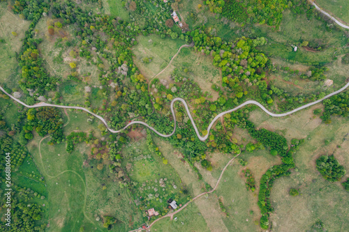 Drone view of green meadows, small houses and roads in Transylvania, Romania.