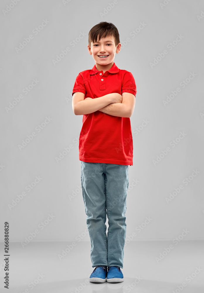 childhood, expressions and people concept - smiling little boy in red polo t-shirt with crossed arms over grey background childhood, expressions and people concept - smiling little boy in red polo t-shirt with crossed arms over grey background