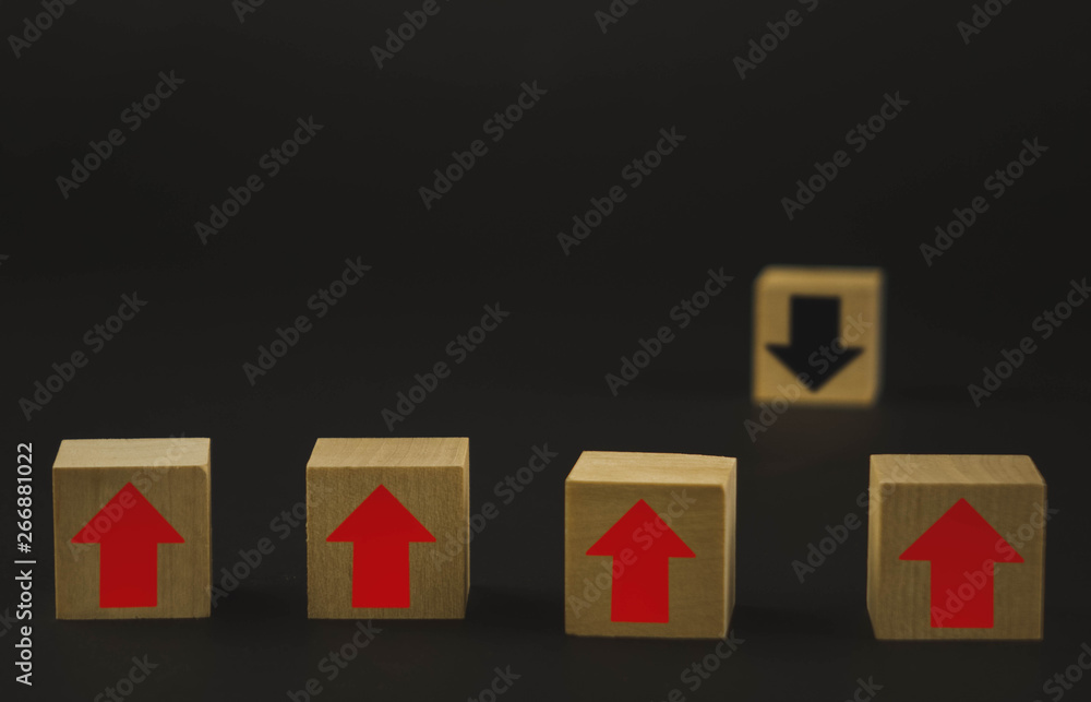 Fototapeta premium Hand putting wood cube block on top pyramid wooden blocks with red arrows facing opposite to the black arrows. With different concepts to other people. Going for success.