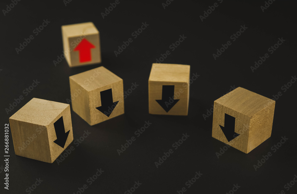 Obraz premium Hand putting wood cube block on top pyramid wooden blocks with red arrows facing opposite to the black arrows. With different concepts to other people. Going for success
