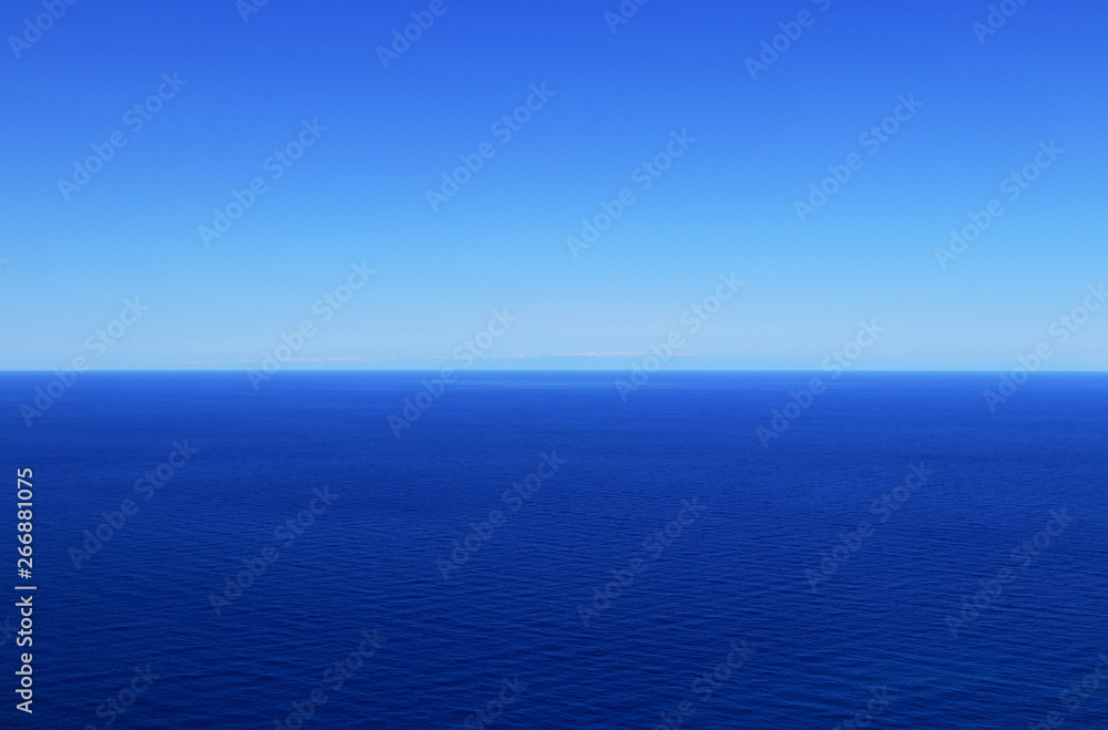 Sky without clouds with changing shades of blue and dark mediterranean sea. In background are Turkey mountains. Sunny summer blue sky and sea. Open ocean in free zone