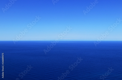 Sky without clouds with changing shades of blue and dark mediterranean sea. In background are Turkey mountains. Sunny summer blue sky and sea. Open ocean in free zone