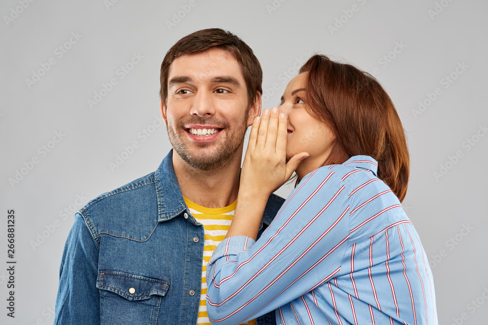 secret and people concept - happy couple whispering over grey background secret and people concept - happy couple whispering over grey background