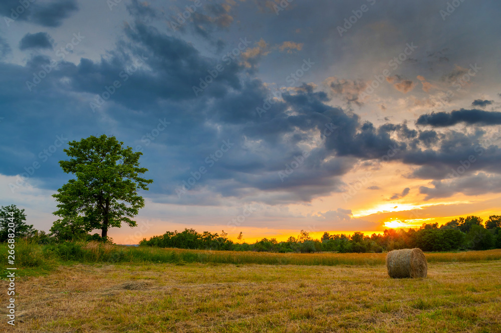 Hay bale at sunset. Sun rays filling up the sky.,