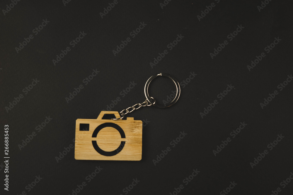 wooden trinket in the form of a camera on a black background. keychain wooden trinket in the form of a camera on a black background. keychain