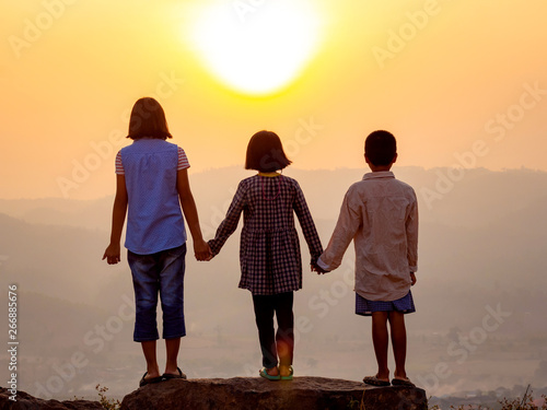 Silhouette group children standing playing on mountain at sunset or sunrise time.