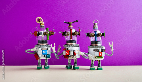 Funny glass headed ufo robots against purple wall background. Three humanoid toy robots communicate.