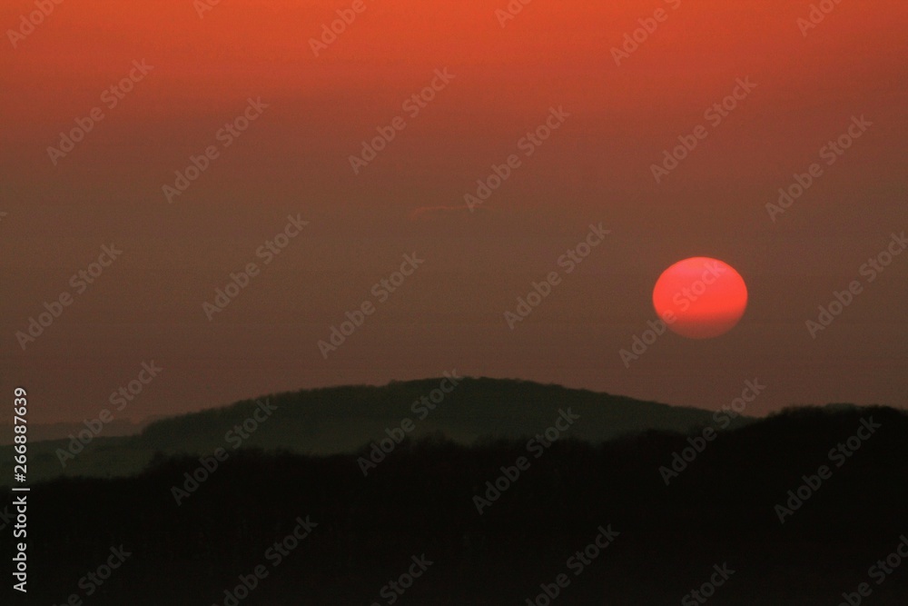 the sun sets over a hill