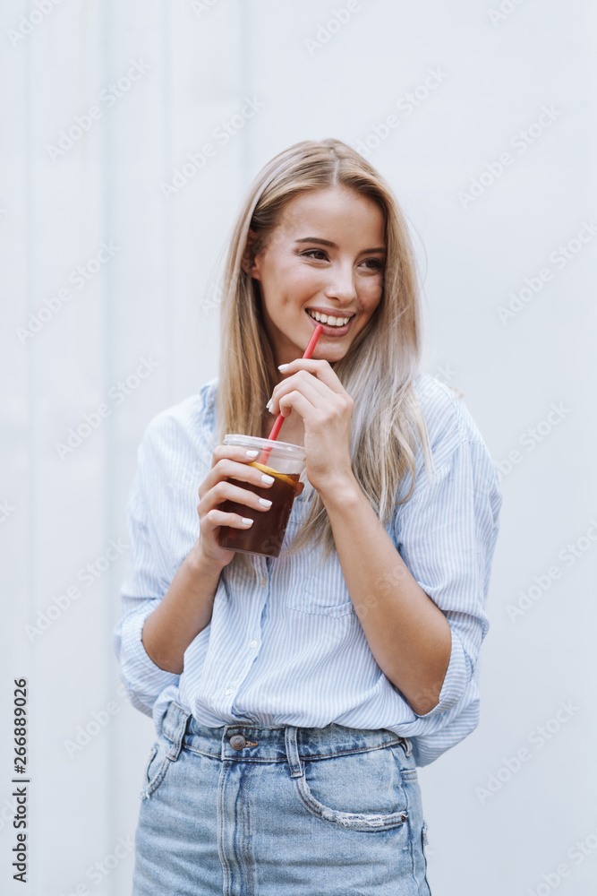 Smiling young girl drinking juice while standing Smiling young girl drinking juice while standing