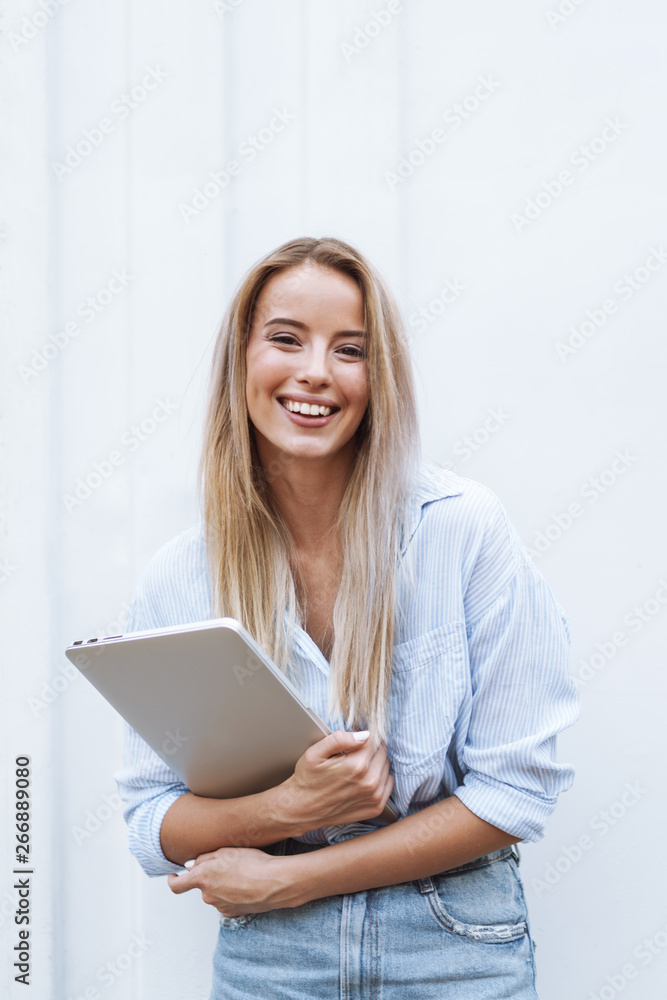 Fototapeta premium Beautiful smiling girl holding laptop computer