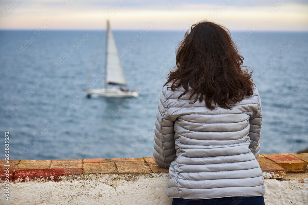 Fototapeta premium Woman looking at infinite sea and sailboat