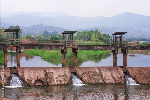 Landscape rural of old irrigation canal concrete control dam on mountains with sky background in Thailand