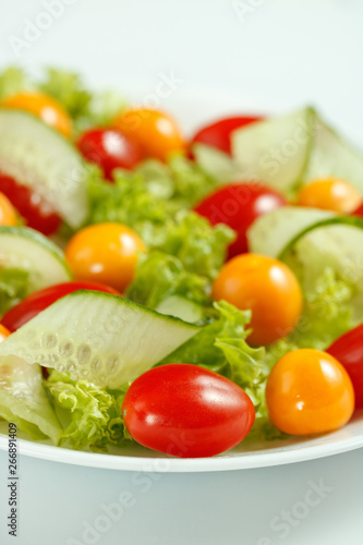 healthy vegan lunch with green salad and red yellow tomatoes on a white background