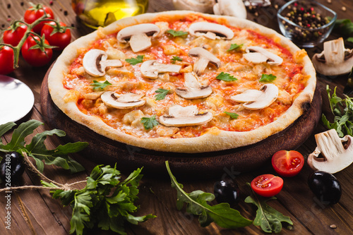 italian pizza with chicken and mushrooms on the wooden dark background (close).