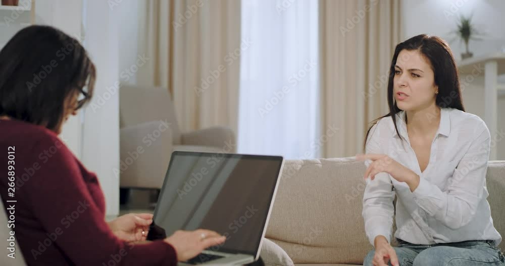 Patient attractive womna with upset face have a therapy session with a psychologist they sitting on the couch and speaking about the mental problems. Patient attractive womna with upset face have a therapy session with a psychologist they sitting on the couch and speaking about the mental problems.