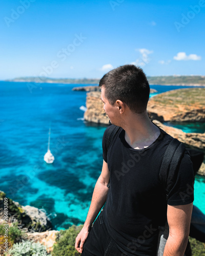 Young man look at sea on the edge of cliffs. Travel and active life concept. Summer seascape.