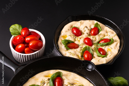 Food concept rising dough for vegan Homemade organic Focaccia in skillet iron pan on black background with copy space
