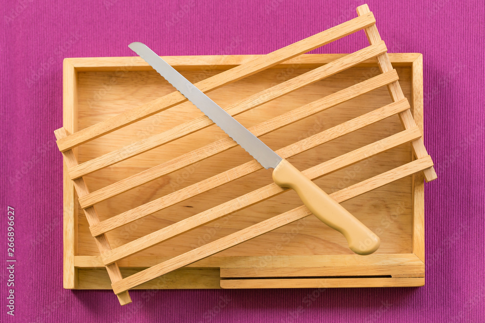 Kitchenware, Vintage cutting bread wood block and tray with stainless steel knife on purple tablecloth background