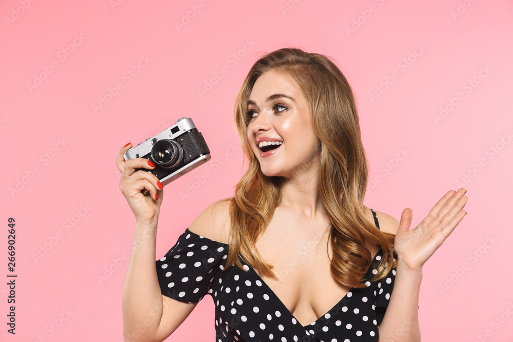 Young pretty woman posing isolated over pink wall background holding camera. Young pretty woman posing isolated over pink wall background holding camera.
