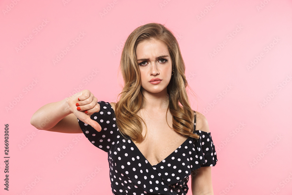 Beautiful displeased sad young pretty woman posing isolated over pink wall background showing thumbs down. Beautiful displeased sad young pretty woman posing isolated over pink wall background showing thumbs down.