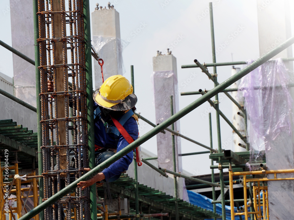 Construction workers working on scaffolding with blue sky at construction site Construction workers working on scaffolding with blue sky at construction site