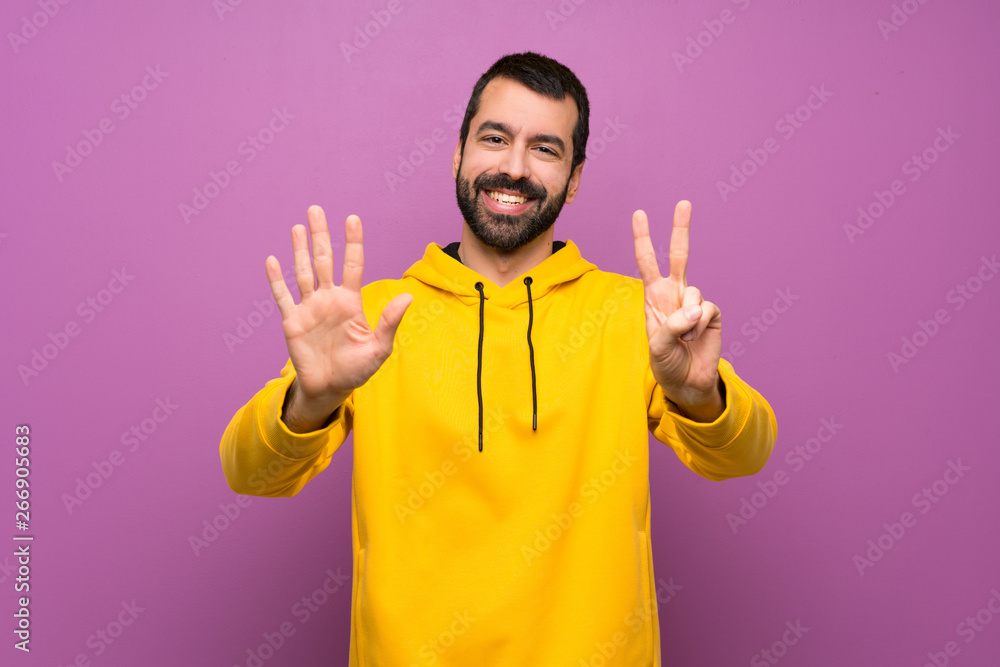 Handsome man with yellow sweatshirt counting seven with fingers Handsome man with yellow sweatshirt counting seven with fingers