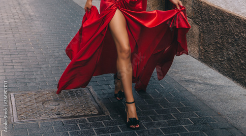 Girl in red. A girl with long slender tanned legs. In a long red fluttering dress. Running down the street