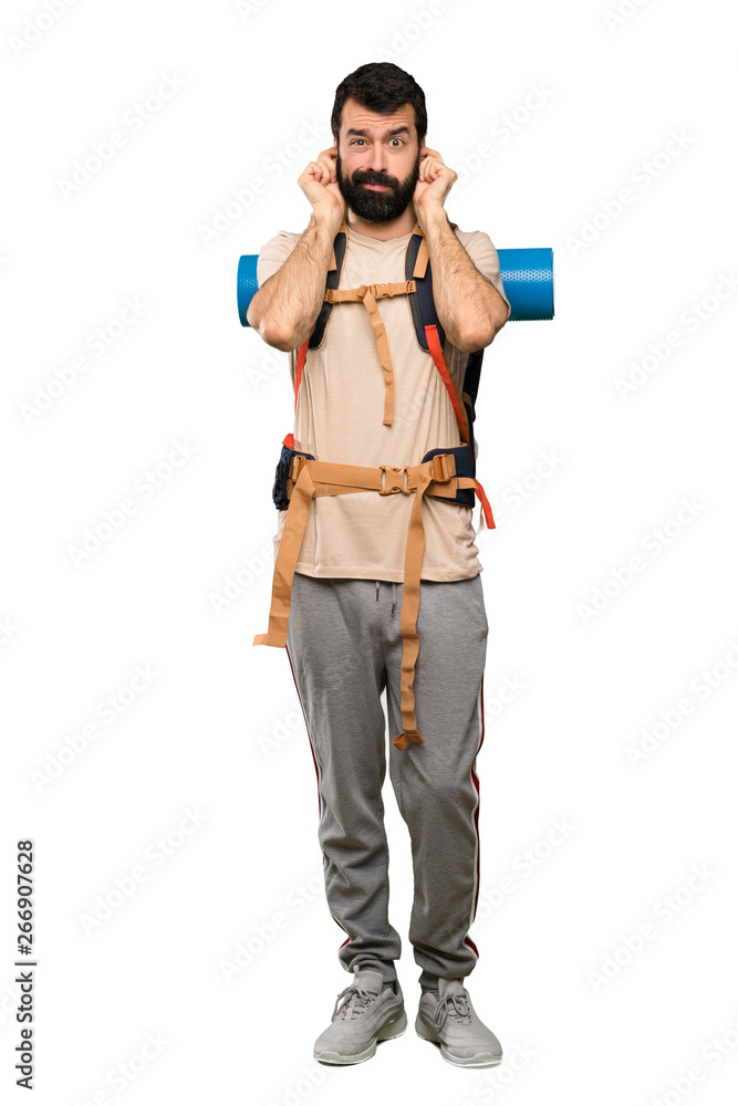 Hiker man frustrated and covering ears over isolated white background Hiker man frustrated and covering ears over isolated white background