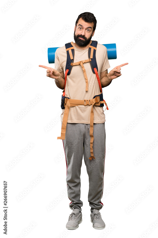 Hiker man pointing to the laterals having doubts over isolated white background Hiker man pointing to the laterals having doubts over isolated white background