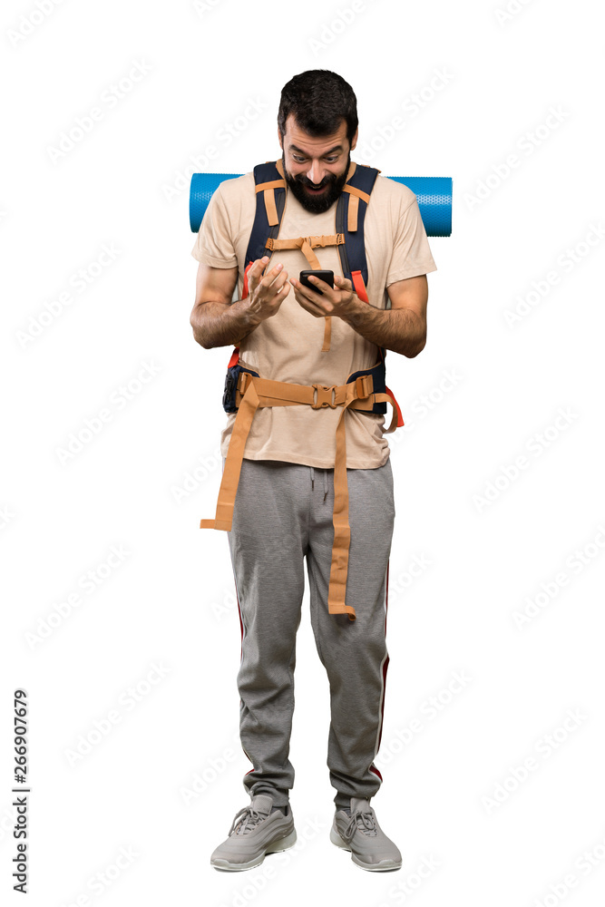 Hiker man surprised and sending a message over isolated white background Hiker man surprised and sending a message over isolated white background